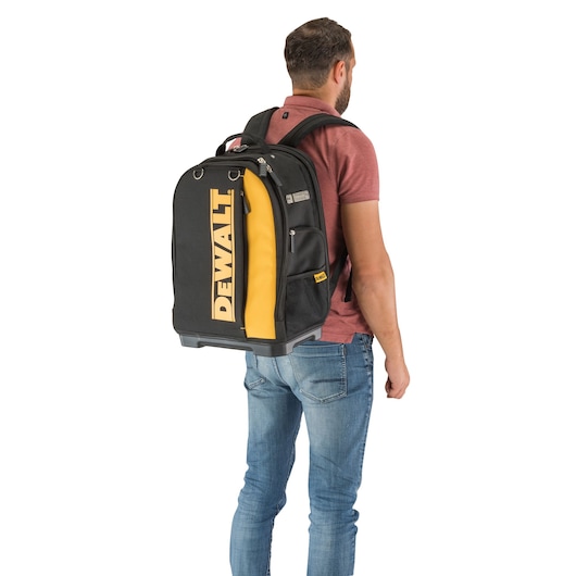 Person carrying a DEWALT DWST81690-1 black and yellow backpack with logo, seen from the back.