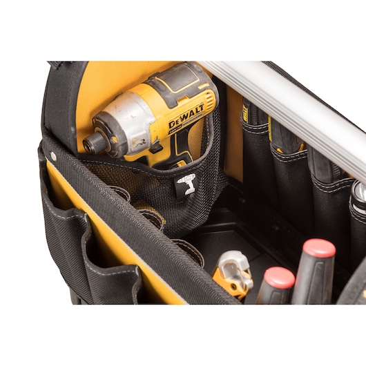 Close-up of a DEWALT tool bag containing a yellow and black cordless impact driver and several hand tools organized in pockets.