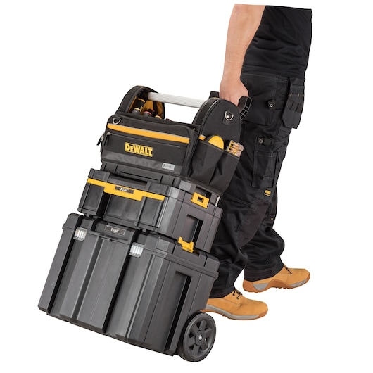 A person is rolling a stack of DEWALT branded toolboxes and a tool bag on wheels. The cases are black with yellow accents and are designed for organizing and transporting tools.