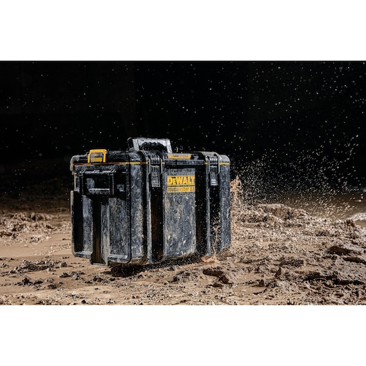 A DEWALT ToughSystem 2.0 tool box is shown in rugged conditions, with mud splashing around it, highlighting its durability