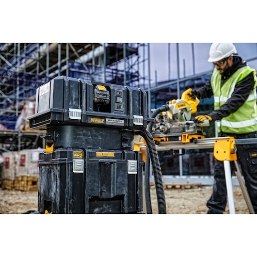 DEWALT DWST83346-1 tool storage box on a construction site, with a worker in a safety vest and hard hat using a circular saw