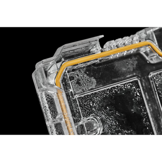 Close-up of a clear DEWALT case lid with orange seal and water droplets inside, shown against a black background.