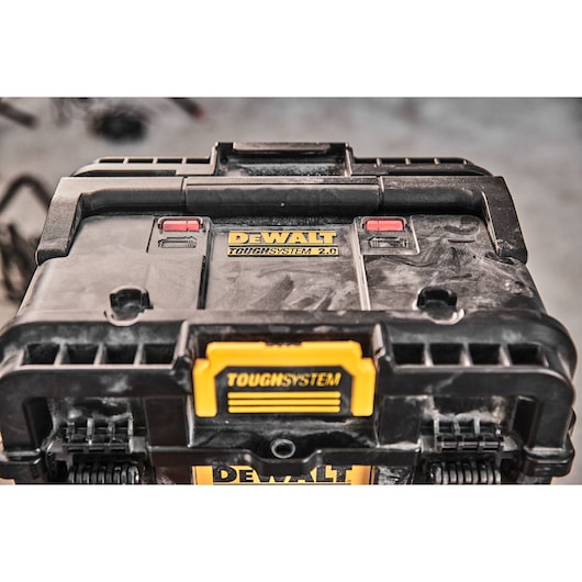 Close-up of a DEWALT ToughSystem 2.0 black and yellow tool storage box on a workshop floor.