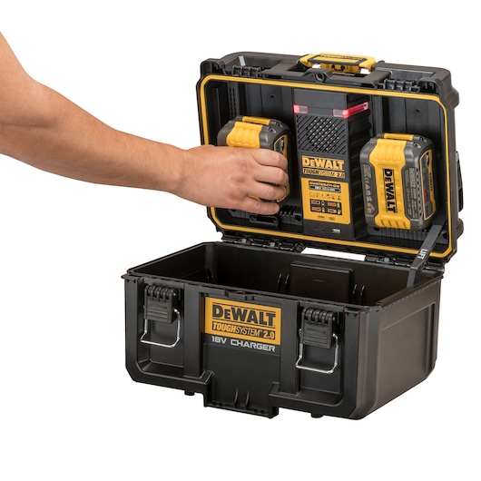 A DEWALT ToughSystem 2.0 18V charger case with batteries, shown with a hand inserting a battery into the charger.
