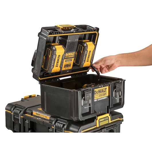 DEWALT ToughSystem 2.0 battery charger box open, hand lifting lid, stacked with tool storage cases.