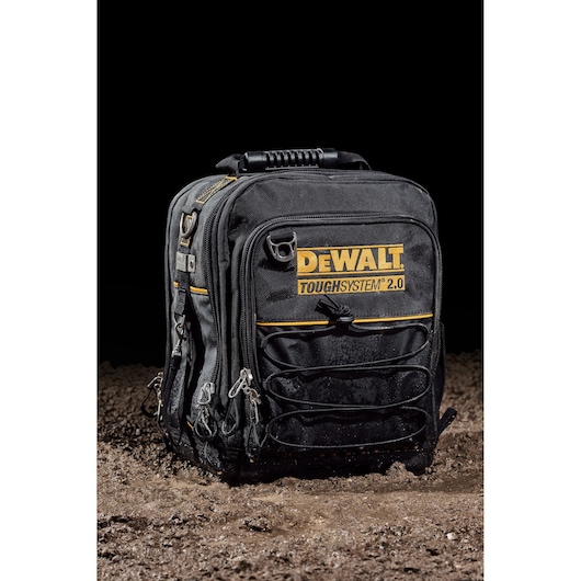 DEWALT ToughSystem 2.0 black backpack with yellow branding on wet ground, multiple compartments visible.