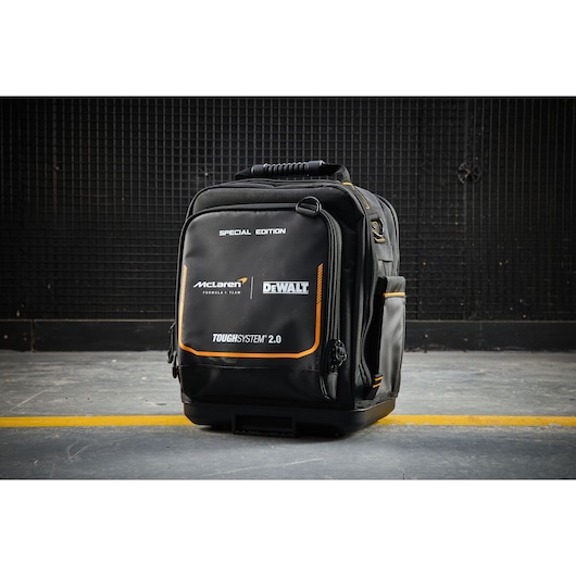 Black DEWALT ToughSystem 2.0 McLaren special edition tool bag with orange accents, shown on a concrete floor.
