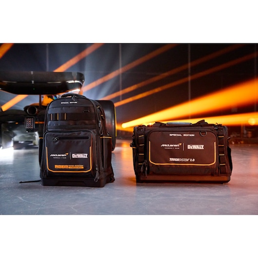 Two DEWALT McLaren bags with logos, a backpack and a tool bag, shown with orange lights and a race car in background.