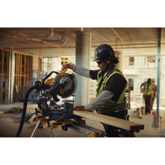 DEWALT saw DCS782N and DCS782XW2 in use at construction site. Worker cutting wood. Photography category.